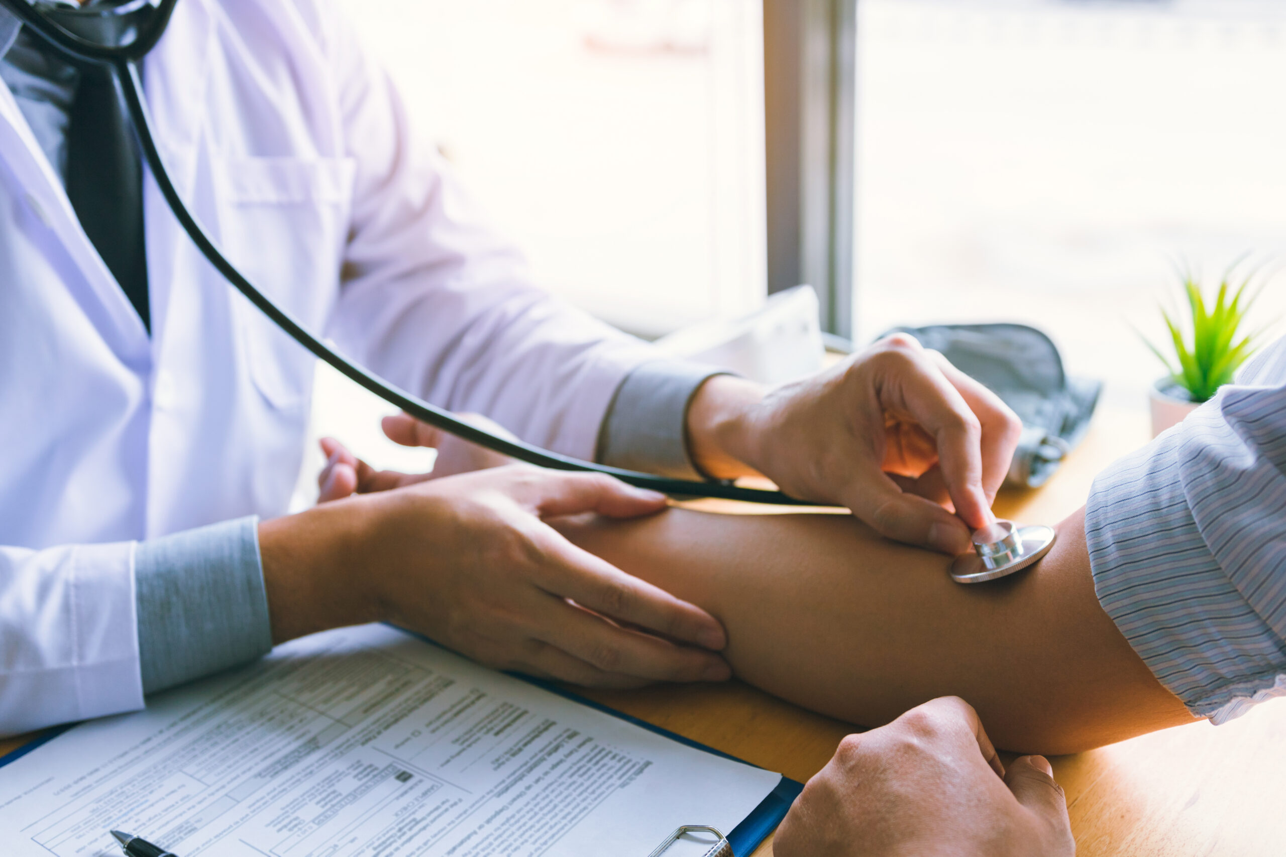 Asian doctor is using the stethoscope to touch the patient's arm.