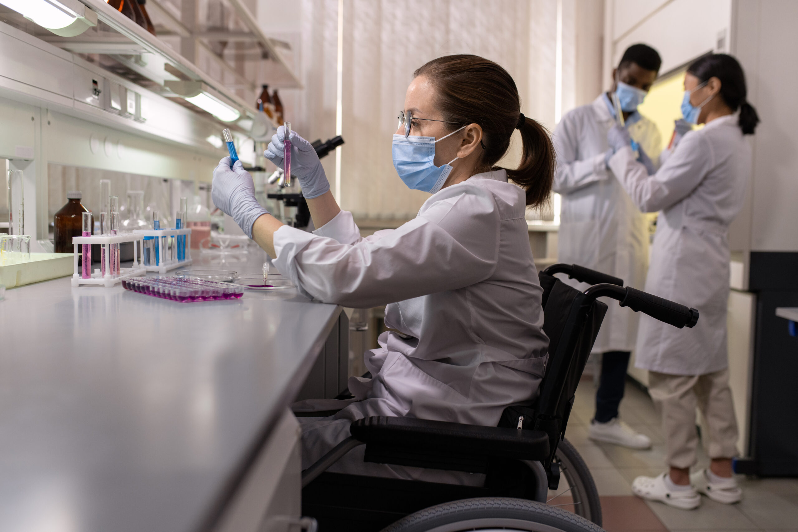 Side view of female scientist in workwear looking at flasks with fluids
